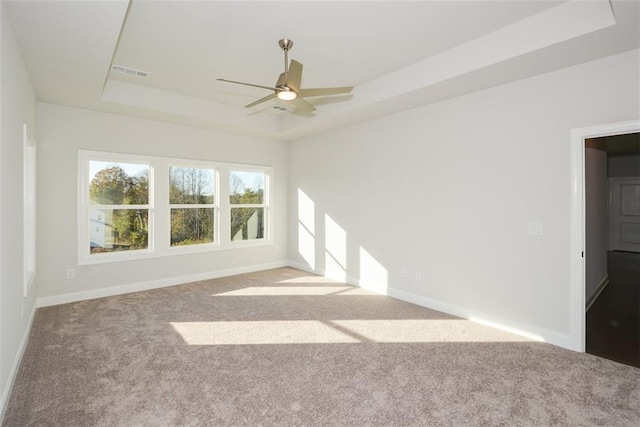 spare room featuring a tray ceiling, ceiling fan, and light colored carpet