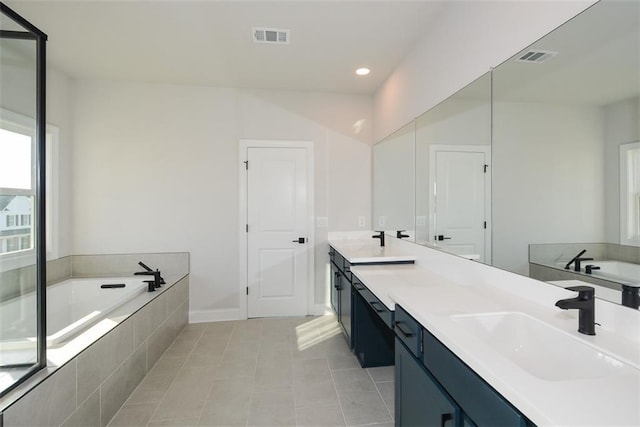 bathroom with vanity, tile patterned floors, and tiled tub