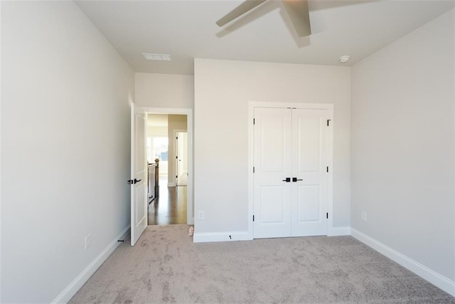 unfurnished bedroom featuring ceiling fan, light carpet, and a closet