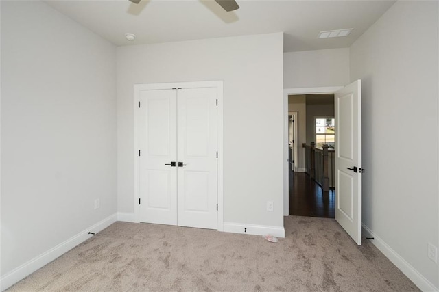 unfurnished bedroom featuring ceiling fan, a closet, and light colored carpet