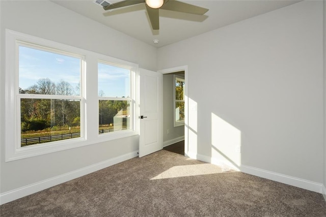 empty room featuring a wealth of natural light, ceiling fan, and carpet