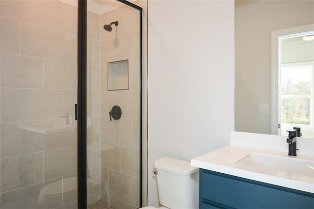 bathroom featuring vanity, toilet, and a shower with shower door