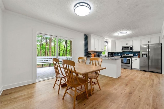 dining room with crown molding, a textured ceiling, and light wood-type flooring
