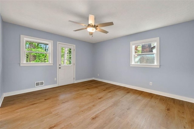 spare room featuring light wood-style floors, baseboards, a ceiling fan, and visible vents