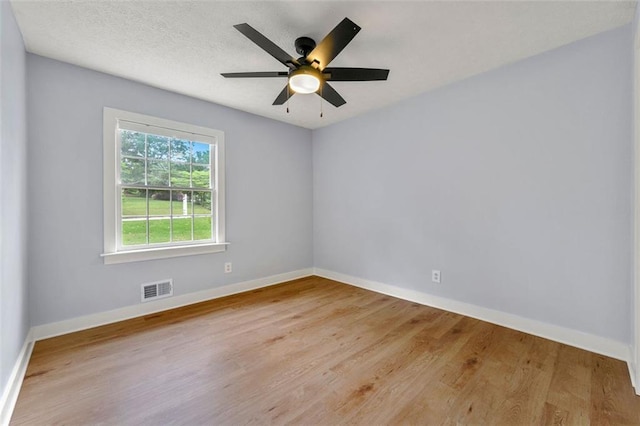 unfurnished room with ceiling fan, baseboards, visible vents, and wood finished floors