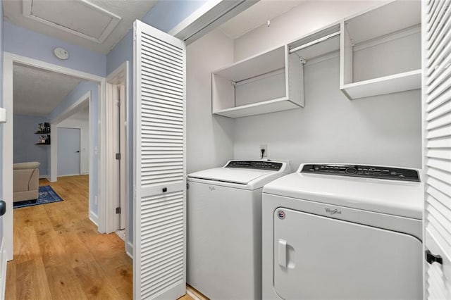 washroom featuring laundry area, attic access, light wood finished floors, and washer and dryer
