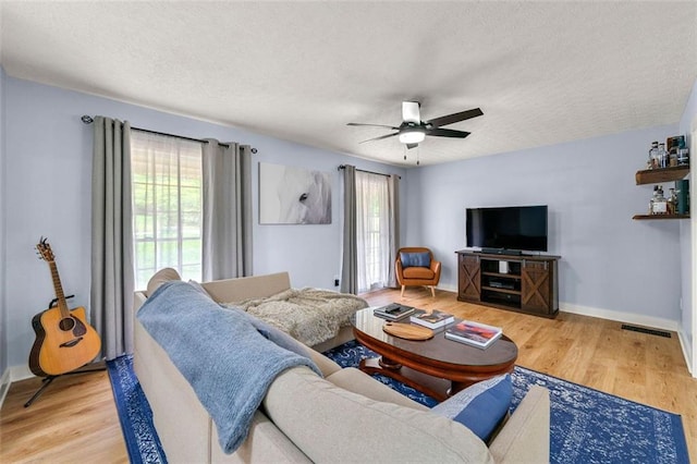 living room featuring a textured ceiling, wood finished floors, and a healthy amount of sunlight