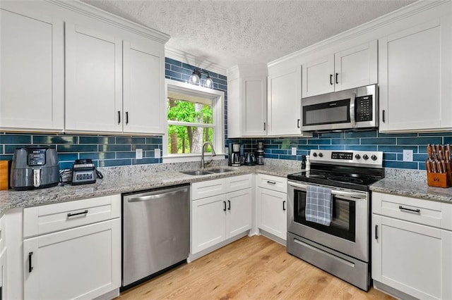 kitchen featuring a sink, a textured ceiling, appliances with stainless steel finishes, and white cabinetry