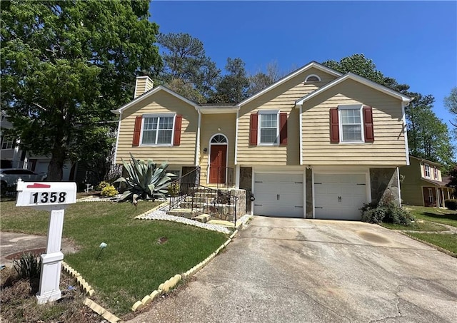 split foyer home featuring an attached garage, a front lawn, a chimney, and concrete driveway
