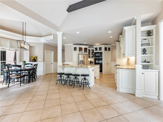 kitchen with light tile patterned floors, a breakfast bar area, black appliances, and white cabinets