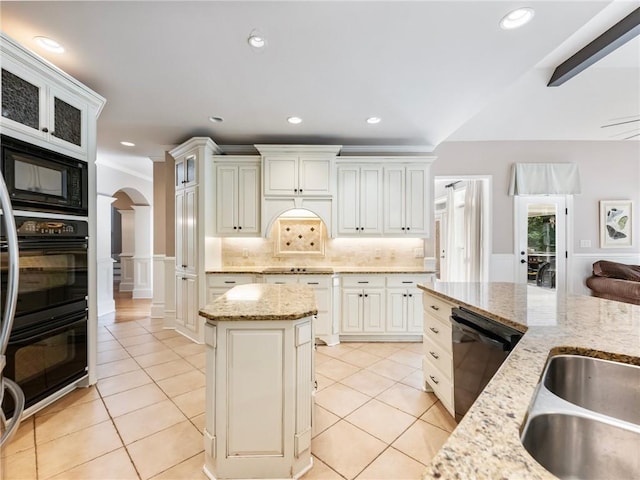 kitchen featuring light stone counters, a center island, light tile patterned floors, and black appliances