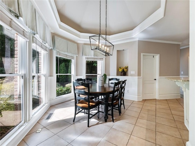 tiled dining area featuring ornamental molding and a tray ceiling