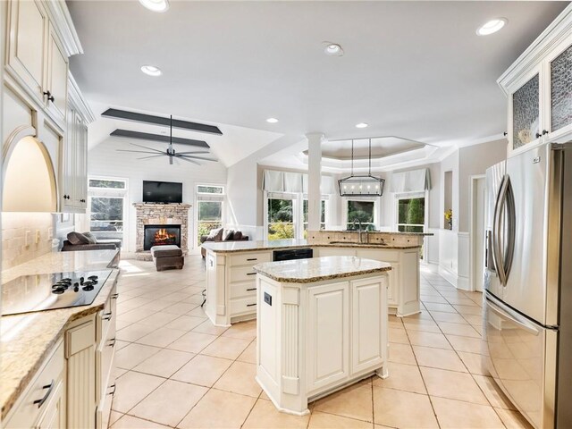 kitchen with sink, light tile patterned floors, black appliances, a kitchen island, and kitchen peninsula