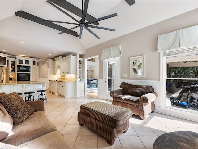 living room with ceiling fan, lofted ceiling, and light tile patterned floors