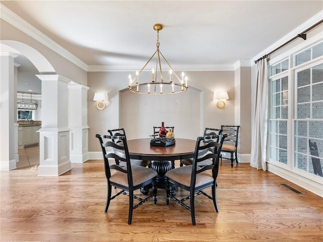 dining room featuring a notable chandelier, ornamental molding, light hardwood / wood-style flooring, and ornate columns