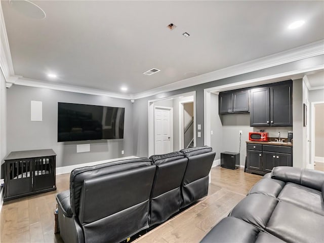 living room featuring sink, crown molding, and light hardwood / wood-style floors