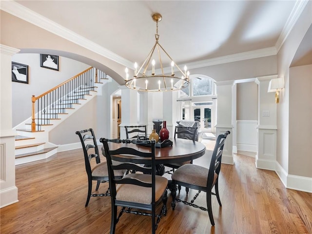 dining room with crown molding, light hardwood / wood-style floors, and ornate columns