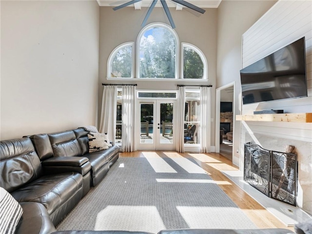 living room with a high ceiling, a premium fireplace, light wood-type flooring, and french doors