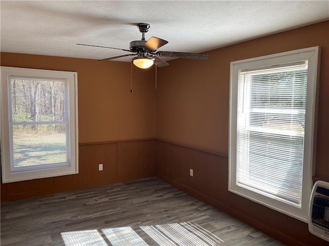 spare room with ceiling fan, hardwood / wood-style floors, heating unit, and a textured ceiling