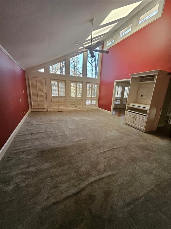 unfurnished living room featuring carpet floors, ceiling fan, and high vaulted ceiling