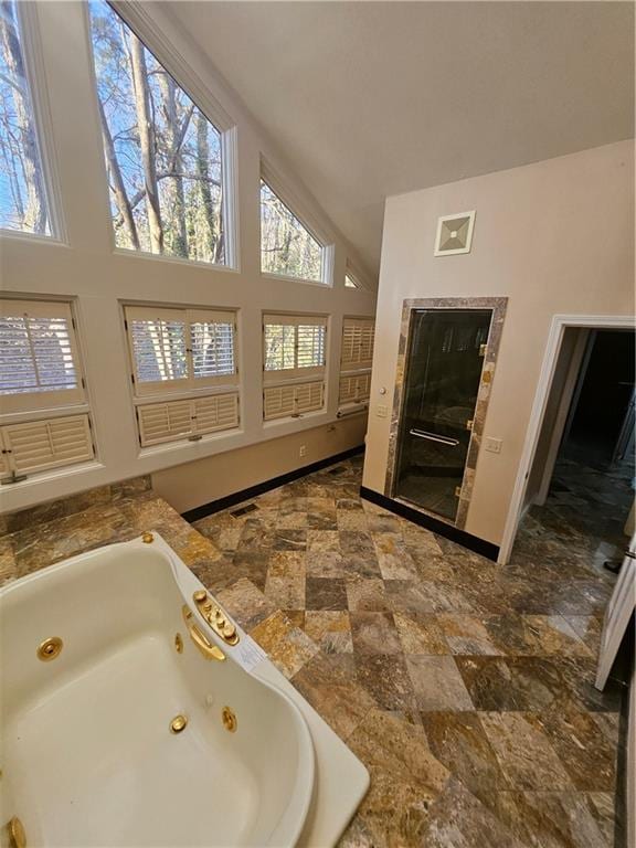 bathroom featuring tiled bath, a wealth of natural light, and vaulted ceiling