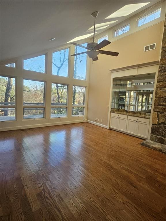 unfurnished living room featuring a towering ceiling, dark hardwood / wood-style floors, and plenty of natural light