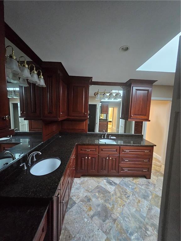 kitchen featuring kitchen peninsula, dark stone countertops, and sink