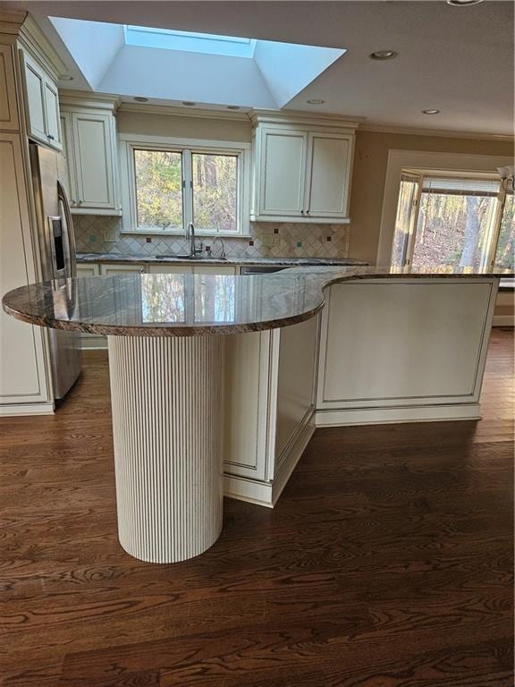 kitchen featuring a center island, sink, a skylight, a healthy amount of sunlight, and light stone counters