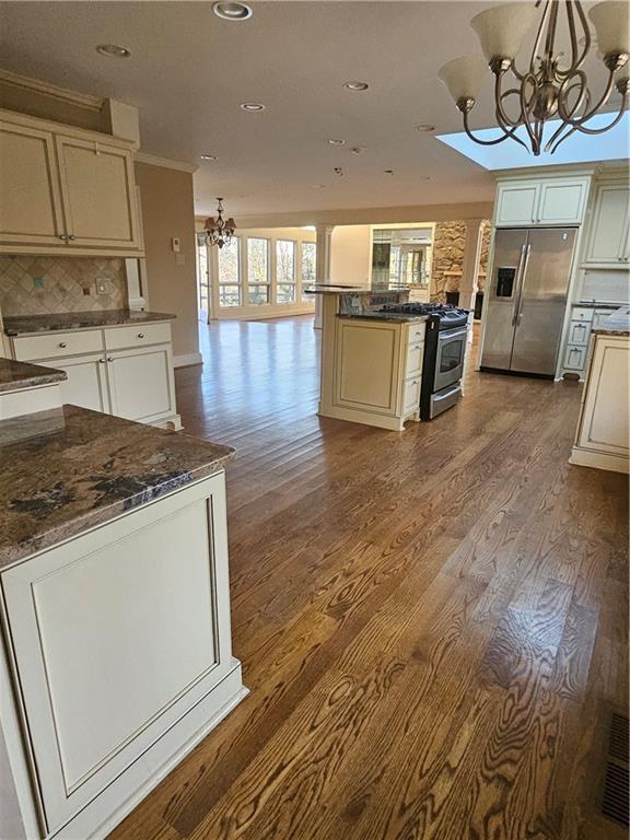 kitchen featuring stainless steel appliances, a chandelier, pendant lighting, decorative backsplash, and light wood-type flooring