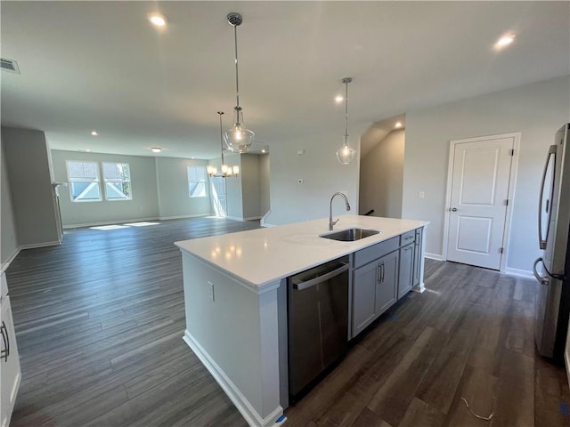 kitchen with sink, decorative light fixtures, appliances with stainless steel finishes, dark hardwood / wood-style flooring, and a kitchen island with sink