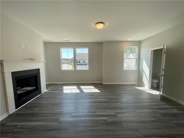 unfurnished living room featuring dark wood-type flooring and a wealth of natural light