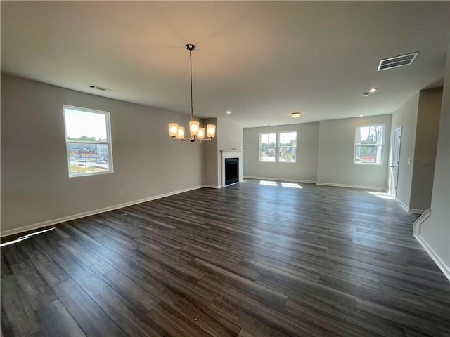 unfurnished living room featuring a notable chandelier and dark hardwood / wood-style floors