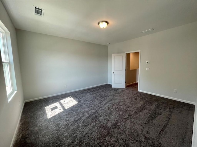 spare room featuring dark carpet