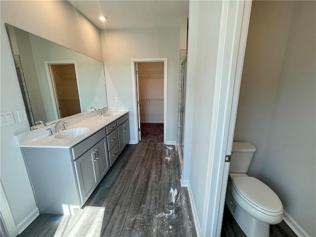 bathroom with vanity, hardwood / wood-style floors, a shower with shower door, and toilet