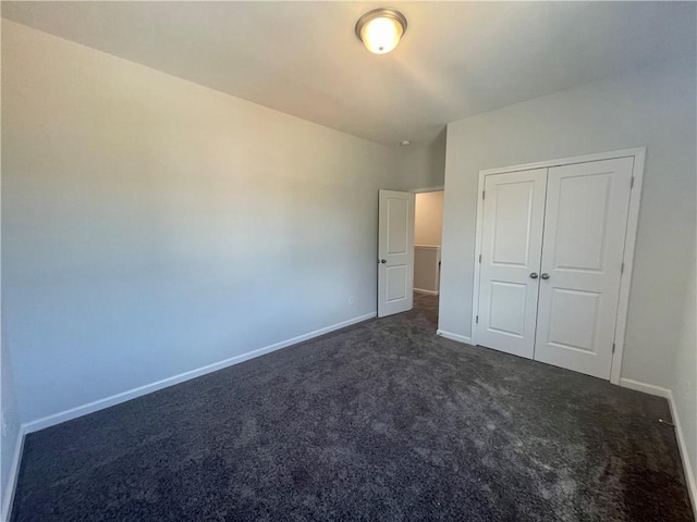 unfurnished bedroom with dark carpet and a closet