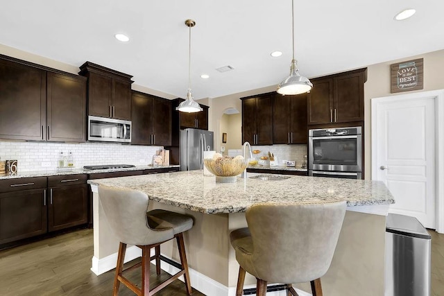 kitchen featuring pendant lighting, an island with sink, sink, a breakfast bar area, and stainless steel appliances