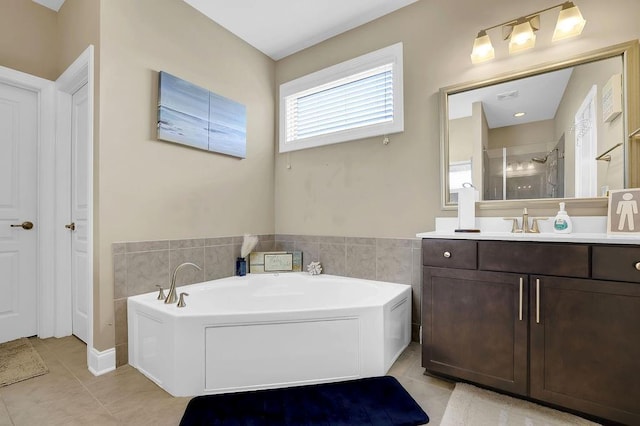 bathroom featuring a garden tub, tile patterned flooring, tile walls, and vanity