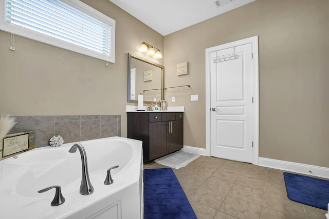 full bath featuring a garden tub, tile patterned flooring, baseboards, and vanity