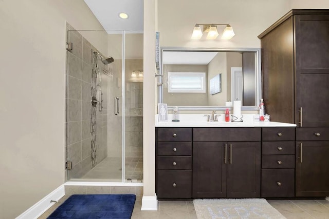 full bath with baseboards, a stall shower, vanity, and tile patterned floors