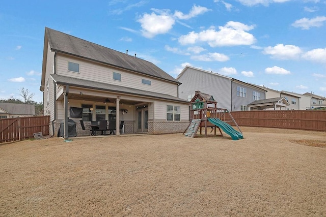 back of house with a patio area, a playground, brick siding, and a fenced backyard