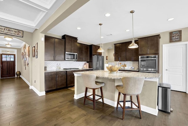 kitchen featuring arched walkways, a kitchen island, a breakfast bar area, stainless steel appliances, and pendant lighting