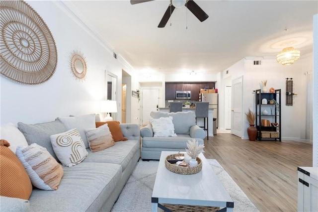 living room featuring ceiling fan, light hardwood / wood-style flooring, and crown molding