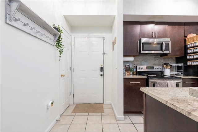 kitchen with tasteful backsplash, dark brown cabinetry, light tile patterned floors, and stainless steel appliances