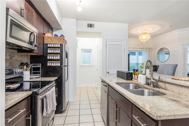 kitchen featuring decorative backsplash, dark brown cabinets, stainless steel appliances, sink, and light tile patterned floors