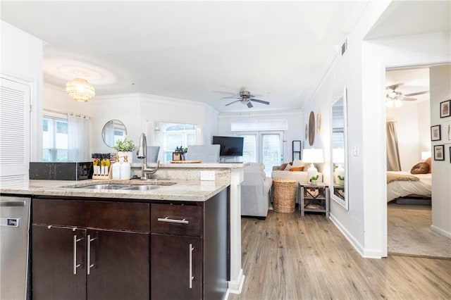 kitchen with light stone counters, stainless steel dishwasher, dark brown cabinets, sink, and light hardwood / wood-style floors