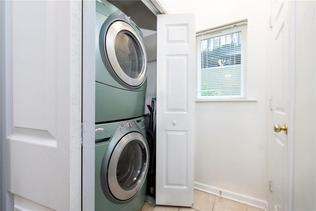 laundry room featuring light tile patterned floors and stacked washer and dryer