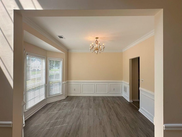 spare room featuring dark wood-type flooring, crown molding, and a notable chandelier