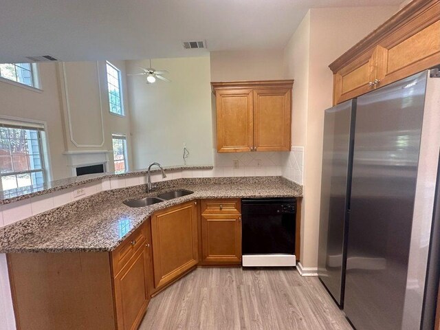 kitchen with ceiling fan, sink, black dishwasher, light hardwood / wood-style floors, and stainless steel refrigerator