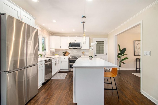 9640 Cedar Grove Rd, Fairburn, GA 30213 - kitchen with appliances with stainless steel finishes, a sink, a breakfast bar area, a kitchen island, and dark wood-style flooring