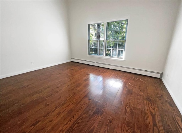 spare room with a baseboard heating unit and dark hardwood / wood-style flooring